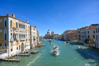 Venecija, Italija: Historijske građevine uz riječni kanal u centru grada. Popularno turističko odredište. Čamci i gondole na vodi.