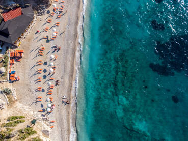 Pješčana plaža i more ljeti, snimak dronom. Ležaljke i suncobrani.