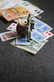 Ilustracija kockara, figure ljudi sa kockom, kartama i novcem.