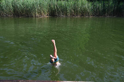 Dječak skače u vodu. Kupanje u rijeci.