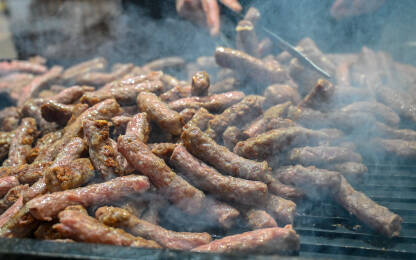 Ćevapčići ili ćevapi na roštilju. Ćevapčići ili ćevapi na roštilju. Čovjek peče meso.