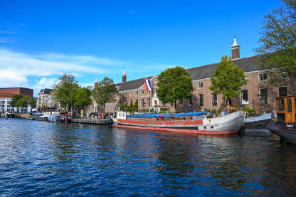 Amsterdam, Nizozemska: Vožnja turističkim brodom kroz kanale. Zgrade uz rijeku. Čamci na vodi.