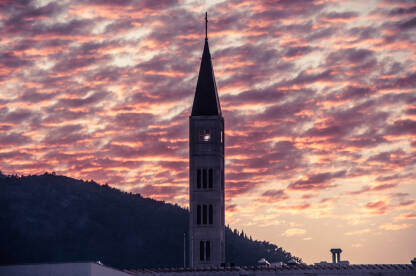 Franjevacka crkva sv. Petra i Pavla u Mostaru slikana iz daljine tokom zalaska sunca.