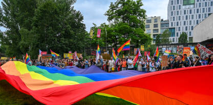 Ogromna dugina zastava i ljudi koji nose zastave i transparente na Povorci ponosa u Sarajevu, 24. jun 2023. Protest za prava LGBTIQ zajednice.