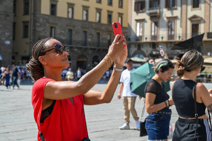 Žena fotografiše telefonom. Žena fotografiše telefonom poznatu znamenitosti u gradu. Turisti fotografišu mobilnim telefonima.