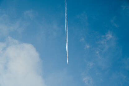 Avion na plavom nebu leti između oblaka. Putovanje avionom.