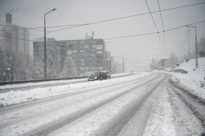 Vožnja automobilom po snijegu u gradu zimi. Opasan zimski put. Zaleđeni putevi. Pahuljice padaju.