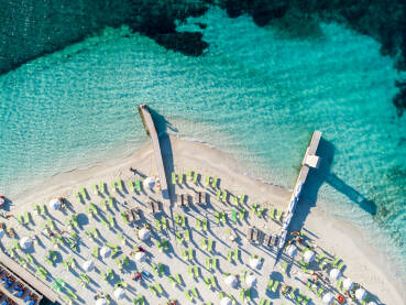 Egzotična pješčana plaža. Ležaljke i suncobrani na tropskoj plaži uz more. Snimci dronom.