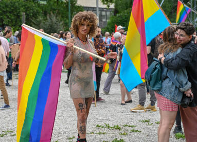 Istetovirana djevojka drži zastavu duginih boja na Povorci ponosa u Sarajevu, 24. juna 2023. Protest za prava LGBTIQ zajednice. Učesnica nosi duginu zastavu.