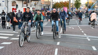 Amsterdam, Nizozemska: Grupa biciklista vozi bicikle po ulici. Biciklizam u  gradu. Ljudi koriste bicikle za vožnju.