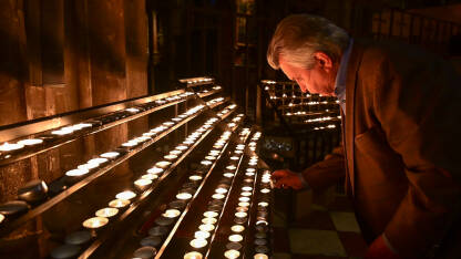 Čovjek pali svijeću u katedrali. Vjernik sa svijećom u crkvi.