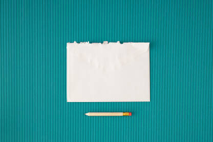Bijela poderana omotnica / kuverta i olovka na plavoj pozadini.