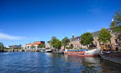 Amsterdam, Nizozemska. Zgrade i kuće uz rijeku. Turistički brodovi na vodi.