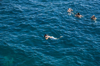 Mladi ljudi se kupaju u moru. Turisti plivaju.