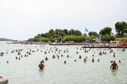 Mnogo kupača u moru na vrhuncu turističke sezone. Ljudi plivaju u moru.