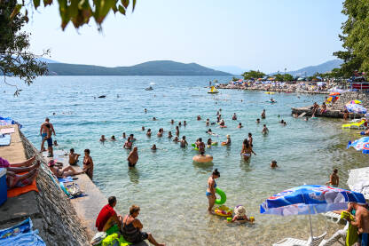 Neum, Bosna i Hercegovina: Grupa ljudi u moru i na plaži. Mladi se zabavljaju na ljetovanju. Ljudi se kupaju u Jadranskom moru.