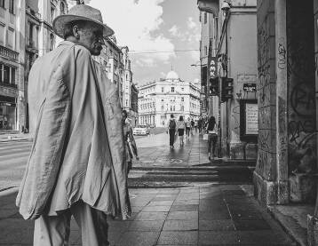 Stariji čovjek u odijelu stoji na ulici u Sarajevu razgleda knjige u izlogu