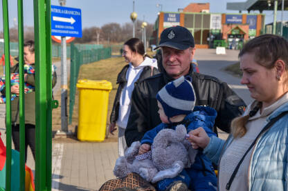Muškarac pomaže majci sa bebom na graničnom prelazu Medyka, Ukrajina-Poljska.