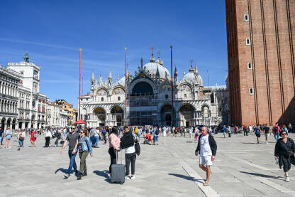 Venecija, Italija: Ljudi šetaju glavnim trgom. Venecija, Italija: Ljudi šetaju glavnim trgom. Piazzetta San Marco. Popularna turistička destinacija. Zvonik, Bazilika svetog Marka i Duždeva palača u centru grada.