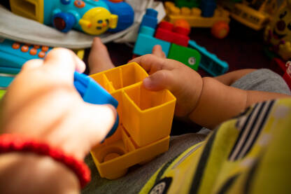 Djecije ruke sklapaju kocke, razbacane igracke i slaganje kockica. Djecija igra, zabava i edukacija.
