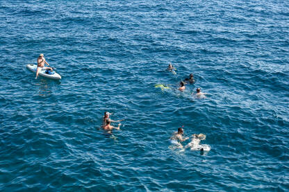 Mladi ljudi se kupaju u moru. Turisti plivaju.