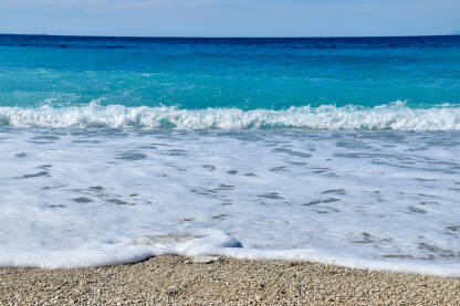 Talasi, morska pjena i čisto plavo more tokom sunčanog dana.