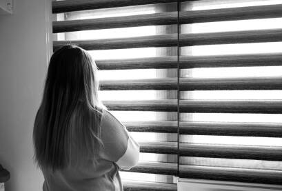 Nasilje nad ženama. Depresivna žena gleda kroz prozor, crno bijela fotografija. Depresivna žena gleda kroz prozor, crno bijela fotografija. Anksiozna djevojka u stanu. Emocionalna kriza. Tužna i zabrinuta žena.