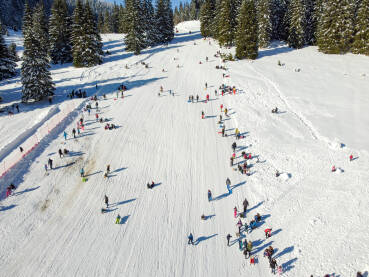 Grupa ljudi se zabavlja na planini. Grupa turista šeta, skija i sanjka se zimi. Snimak dronom: djeca na snijegu. Zimski praznici.