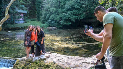 Turisti se fotografišu mobilnim telefonima. Turisti se fotografišu mobilnim telefonima. Grupa turista na Vrelu Bosne u blizini Sarajeva. Ljudi prave fotografije uz izvor rijeke.