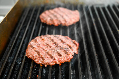 Pečenje hamburgera na roštilju s vrućim ugljenom. Ukusno mljeveno meso se priprema na roštilju. Kuhanje sirovih pljeskavica za hamburger.