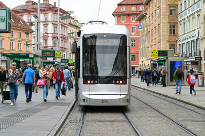 Graz, Austrija: Zgrade na glavnoj ulici. Ljudi hodaju na ulici. Tramvaj sa putnicima. Herrengasse bulevar.