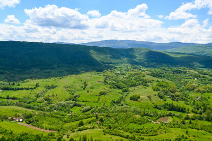 Panorama prirode. Livade, voćnjaci, šuma, brda i planine. Nebo sa oblacima.