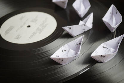 Gramofonska ploča sa malim bijelim papirnim brodićima od nota.