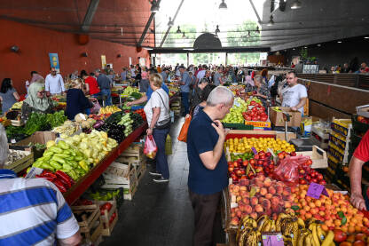 Ljudi kupuju svježe povrće i voće na pijaci. Grupa ljudi na tržnici u kupovini. Kupci kupuju hranu.