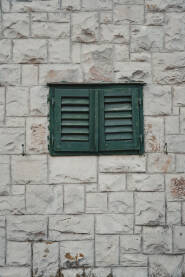 Zid stare dalmatinske kuće sa škurama na prozoru.