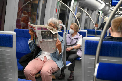 Žena čita novine u metrou. Putnici u podzemnoj željeznici.