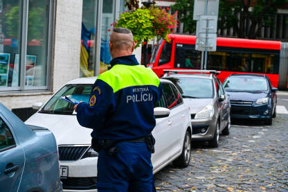Policajac ostavlja kazne za parkiranje na autima u Slovačkoj. Nezakonito parkiranje na ulici. Policajac piše kaznu nepropisno parkiranim automobilima na ulici.