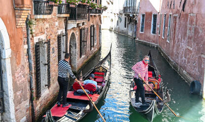Venecija, Italija: Grupa turista uživa u vožnji gondolom. Venecija, Italija: Grupa turista uživa u vožnji gondolom kroz riječni kanal u centru grada. Popularno turističko odredište. Ljudi sjede u gondoli s gondolijerom.