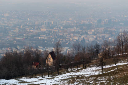 Kuća i voćnjak na brdu i grad Banja Luka u pozadini u izmaglici