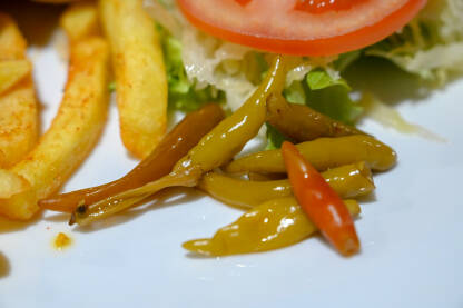 Feferoni servirani na tanjiru u restoranu. Svježa salata. Čili paprika.
