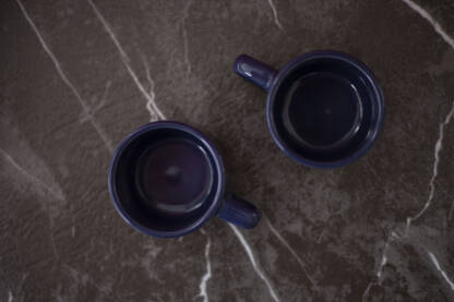 Plave soljice za kafu koje su prazne, pogled odozgo, siva mermer ploca sa belim linijama