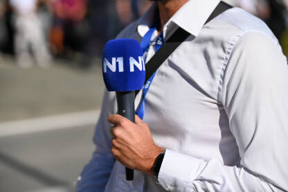 Novinar drži mikrofon. N1 televizija. Novinar drži mikrofon dok izvještava uživo u programu. TV reporter. N1 televizija.