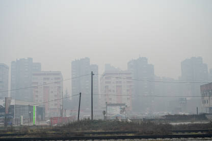 Ekstremno zagađenje zraka u gradu, sa zgradama jedva vidljivim kroz gusti dim i teški smog. Tuzla zimi.