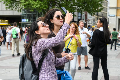 Turisti fotografiraju znamenitosti u centru grada. Ljudi snimaju mobilnim telefonima.