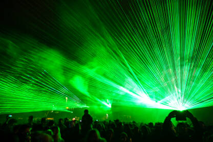 Laserska svjetla i dim na bini tokom koncerta. Raznobojna svjetlosna emisija noću. Apstraktna pozadina. Laserski snop.