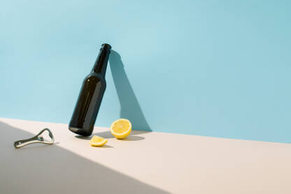 Staklena boca za pivo, metalno otvarač i svježi limun.