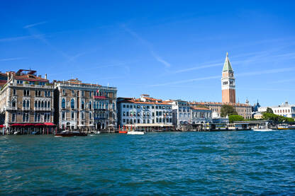 Venecija, Italija: Zvonik na trgu sv. Marka. Historijske građevine uz riječni kanal. Popularno turističko odredište. Brodovi i gondole na moru.