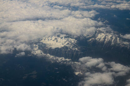 Pogled na planine kroz prozor aviona. Pogled na zemlju kroz oblake. Let avionom.
