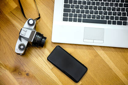 Laptop na stolu sa mobilnim telefonom i kamerom