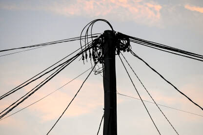 Mnogo električnih kablova na stubu tokom zalaska sunca. Struja. Prijenos električne energije. Električna energija.